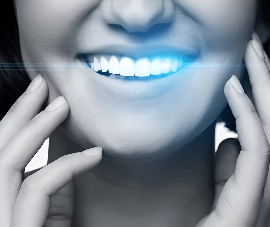 Close-up of a smiling woman’s mouth with glowing blue light highlighting teeth