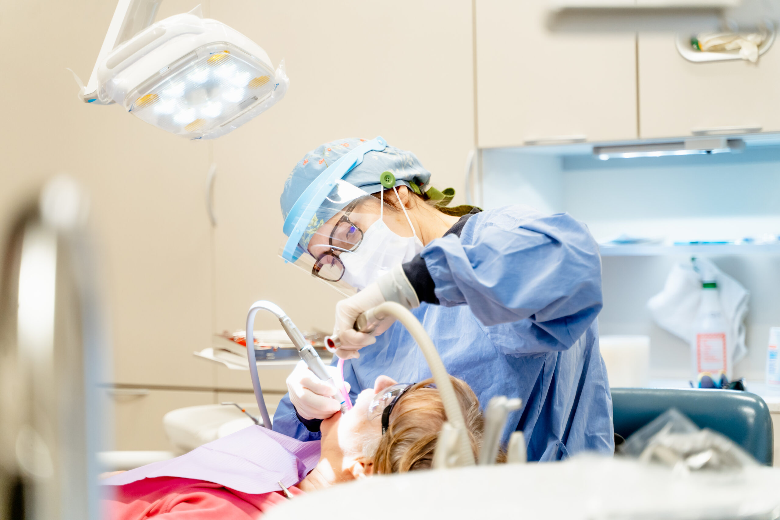 Dentist performing dental procedure on a patient under bright examination light